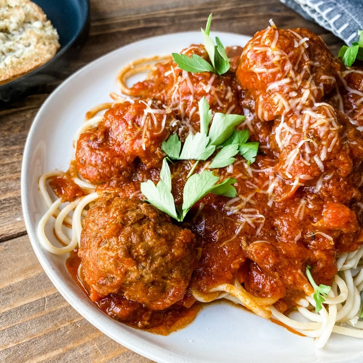 Gluten-free meatballs on a plate of spaghetti with sauce and gluten free garlic bread next to it.