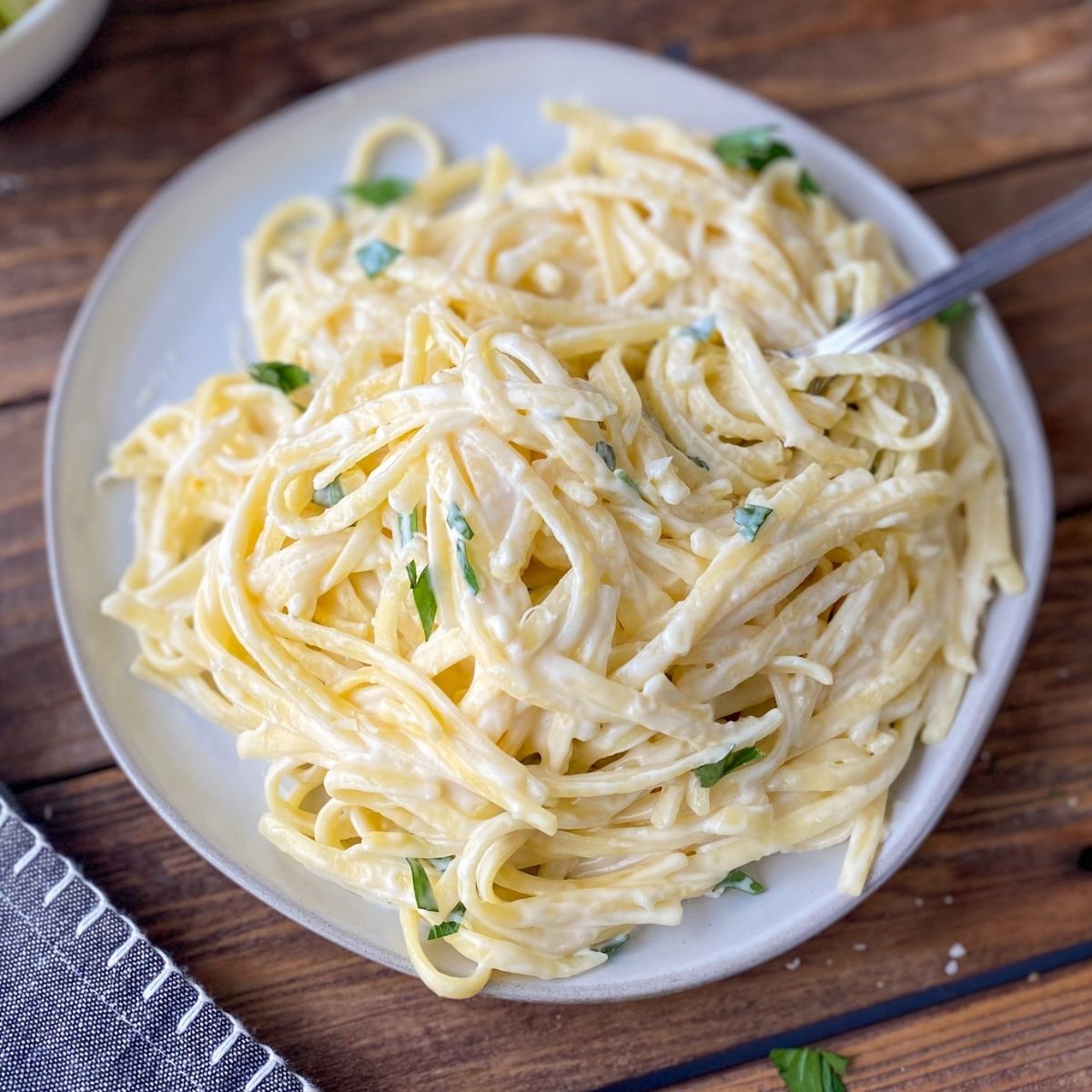 The best gluten-free Alfredo sauce mixed with fettuccine pasta on a plate.