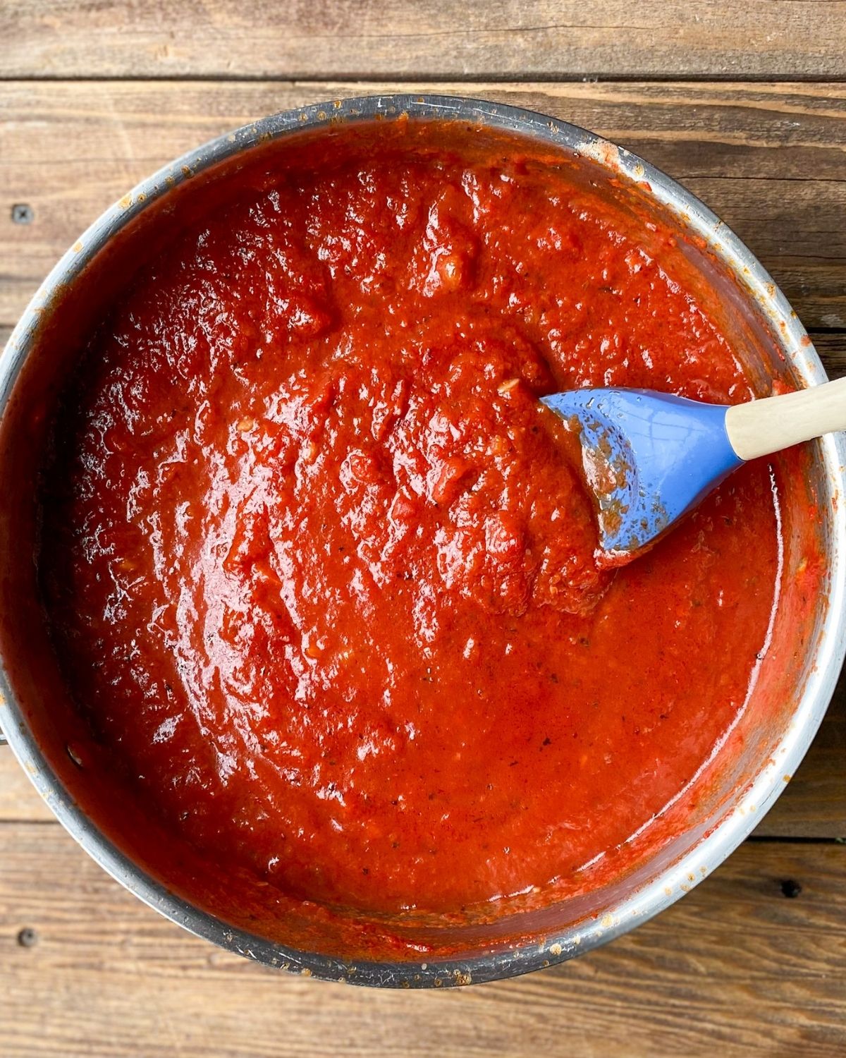 Overhead picture of marinara sauce in a saucepan with a spoon.