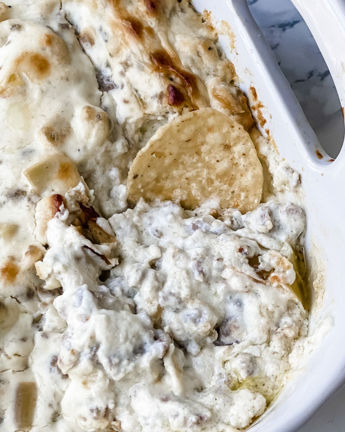 close-up picture of italian sausage dip with a tortilla chip