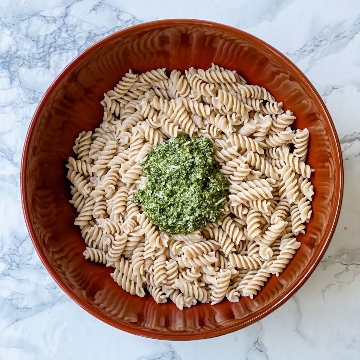pesto on top of the pasta in a large bowl.