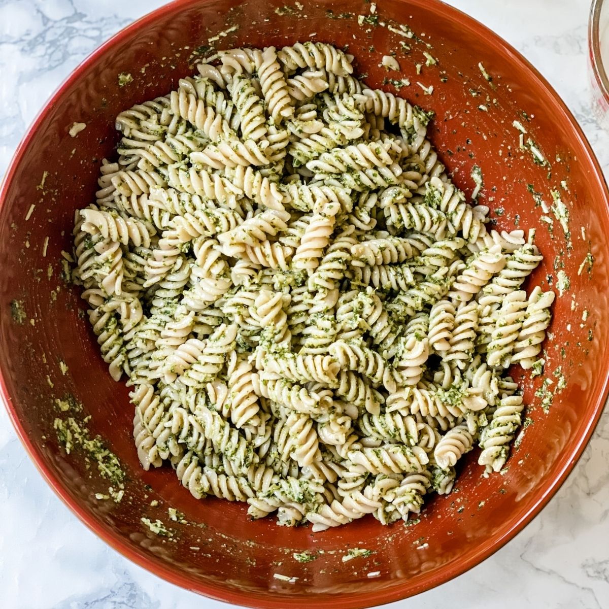 pasta and pesto mixed in a large bowl.