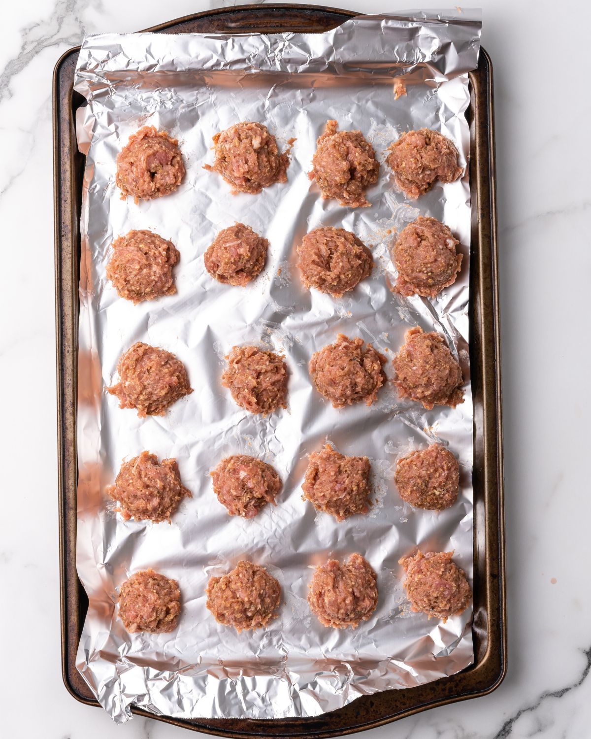 raw turkey meatballs on a sheet pan with foil.