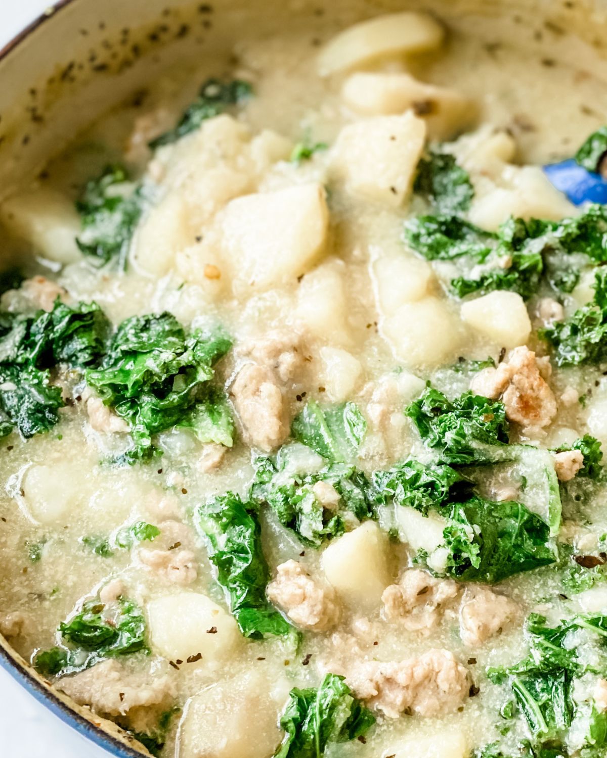close up picture of creamy sausage, potato, and kale soup.