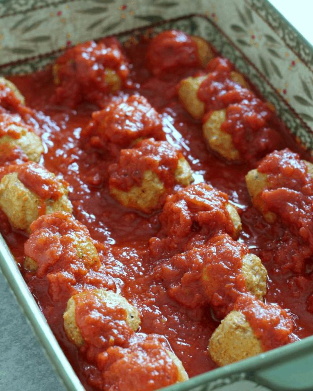 chicken meatballs with sauce in a casserole dish.