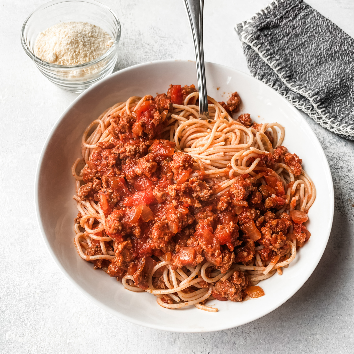 Overhead picture of homemade meat sauce with ground beef and sausage on a white plate.