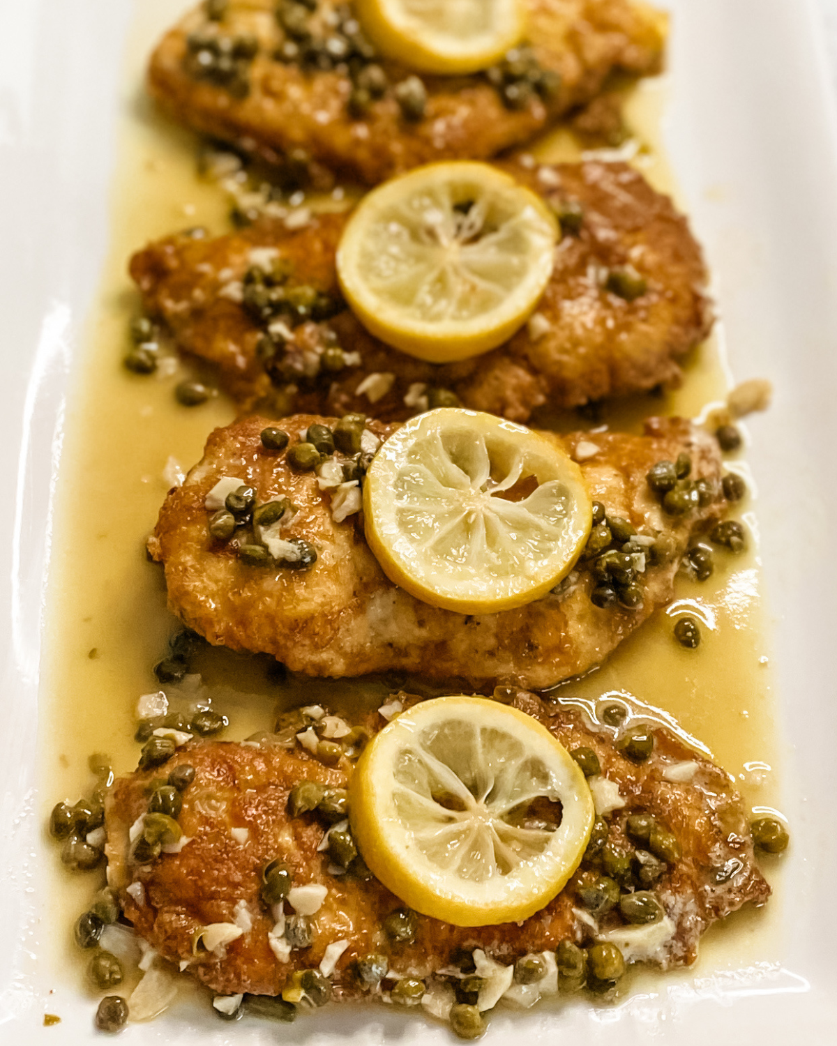 chicken piccata on a platter with lemon on top