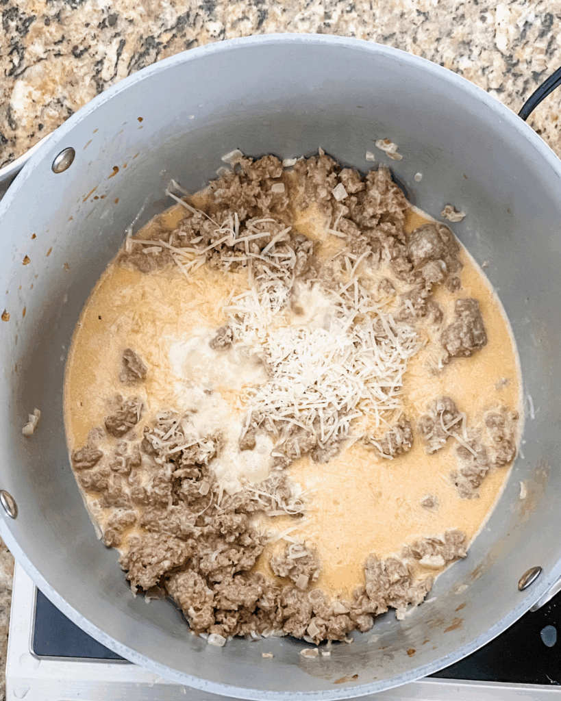add grated cheese into pot with sausage