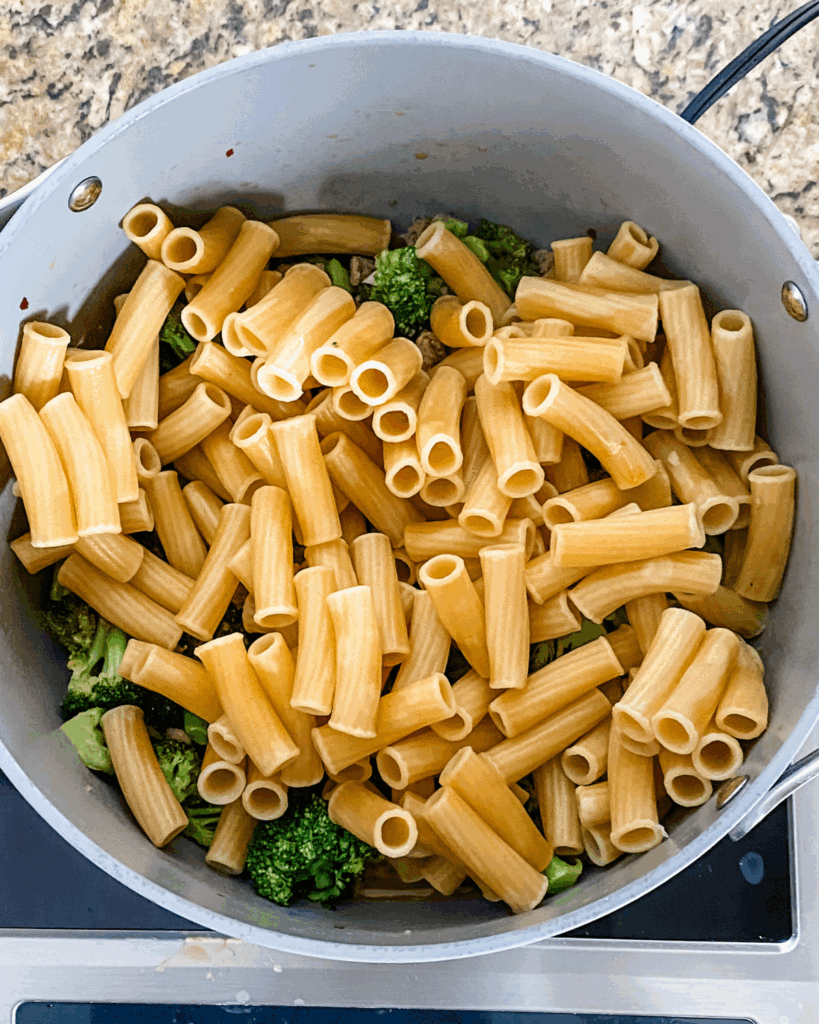 add pasta into the pot with sausage and broccoli.