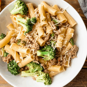 Close-up of sausage broccoli pasta on white plate.