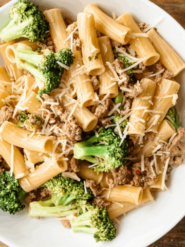 Close-up of sausage broccoli pasta on white plate.