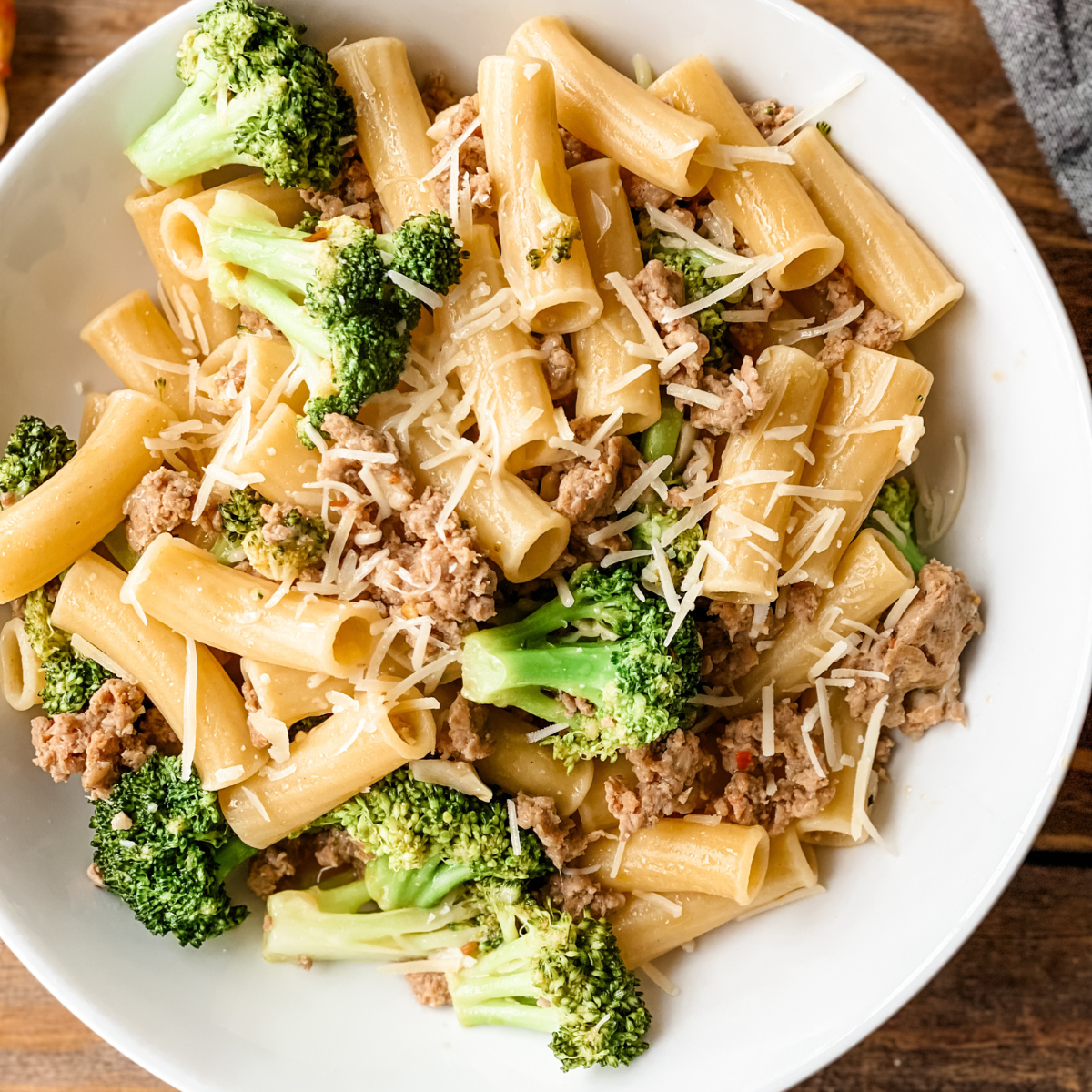 close-up of pasta sausage broccoli on a white plate.